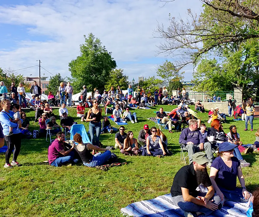 people sitting in lawn chairs and blankets in a park