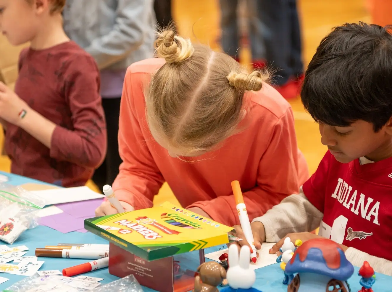 two children coloring with markers at a desk